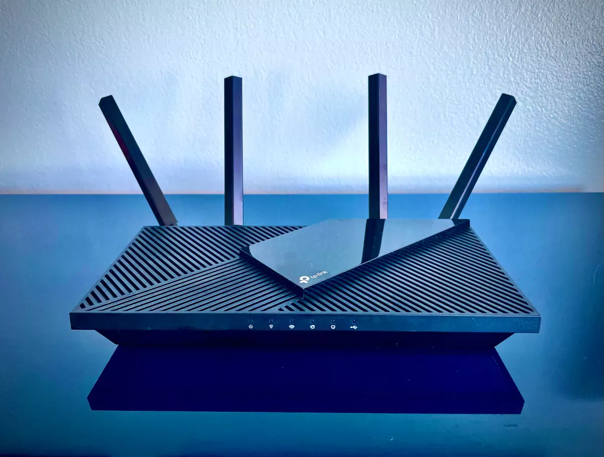The TP-Link Archer AX21 WiFi 6 router on a desk in a home office setting.
